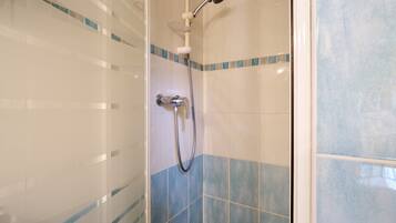Eine Dusche mit Handbrause und Armaturen an der Wand.