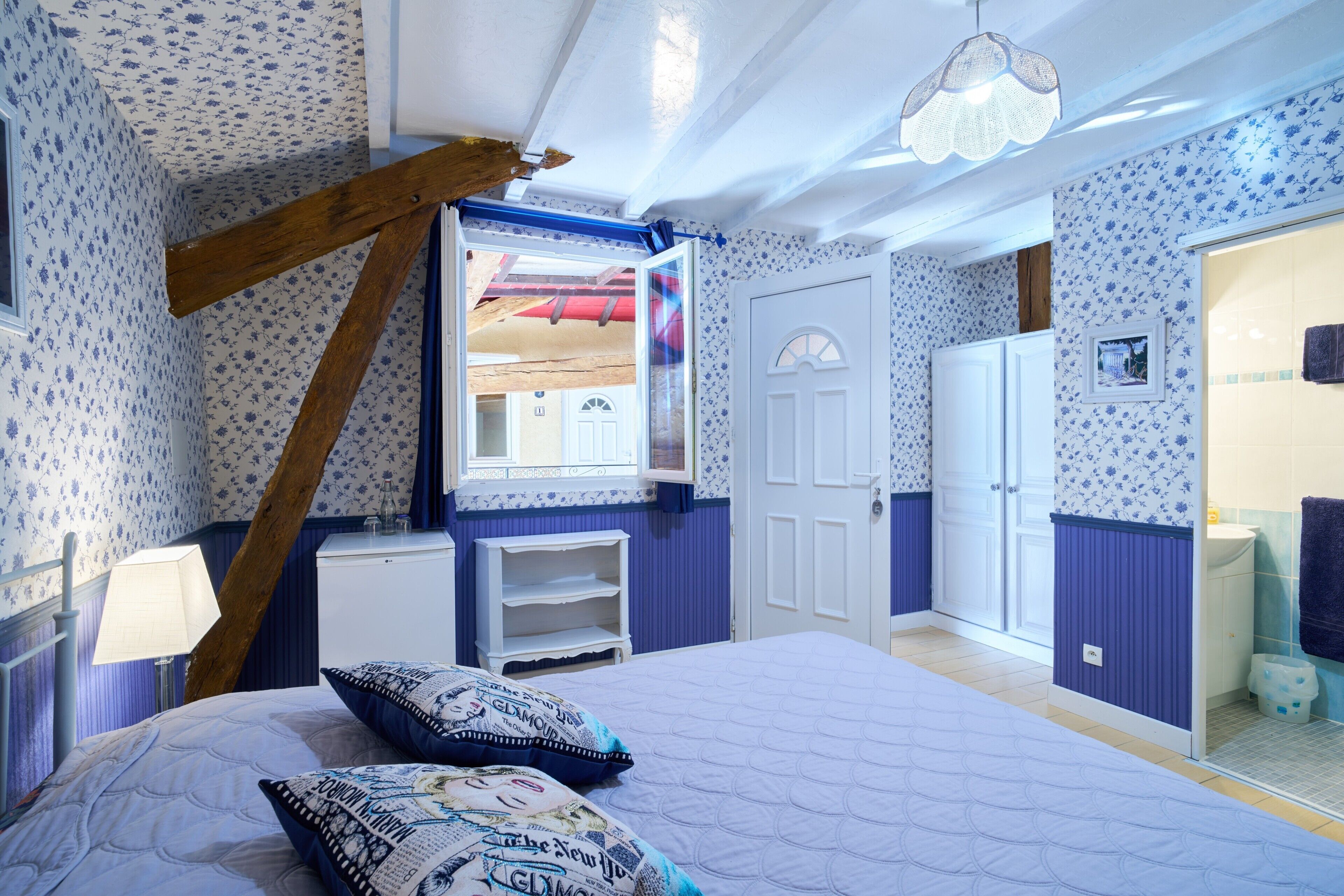 A bedroom with a bed, a dresser, a mirror, and a window.