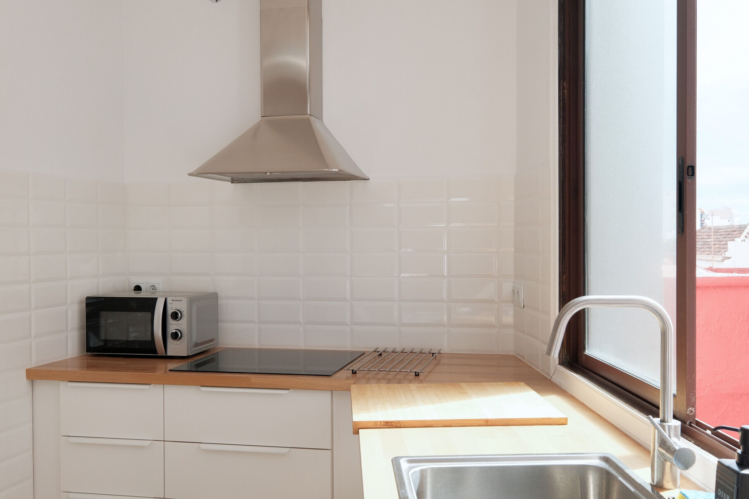 Una cocina con tostadora, campana extractora, ventana y pileta.