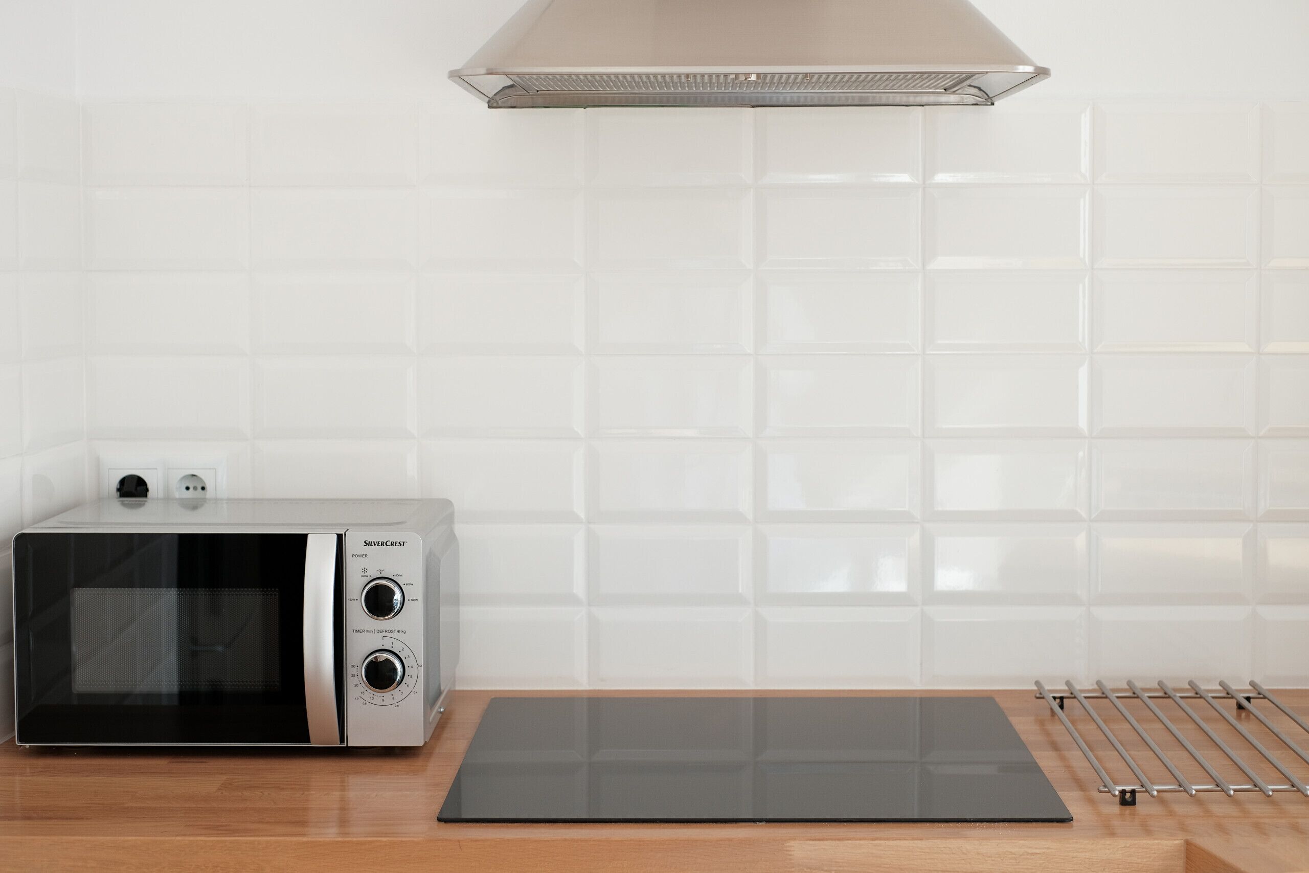A kitchen with a microwave, a black countertop, and a stainless steel range hood.