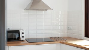 A kitchen with a microwave, a stainless steel range hood, and a wooden countertop.