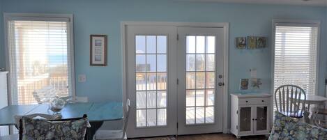 A dining area with a table, chairs, a ceiling fan, and a view through the door.