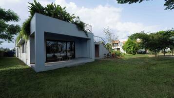 A modern house with a flat roof, large windows, and a small outdoor seating area.