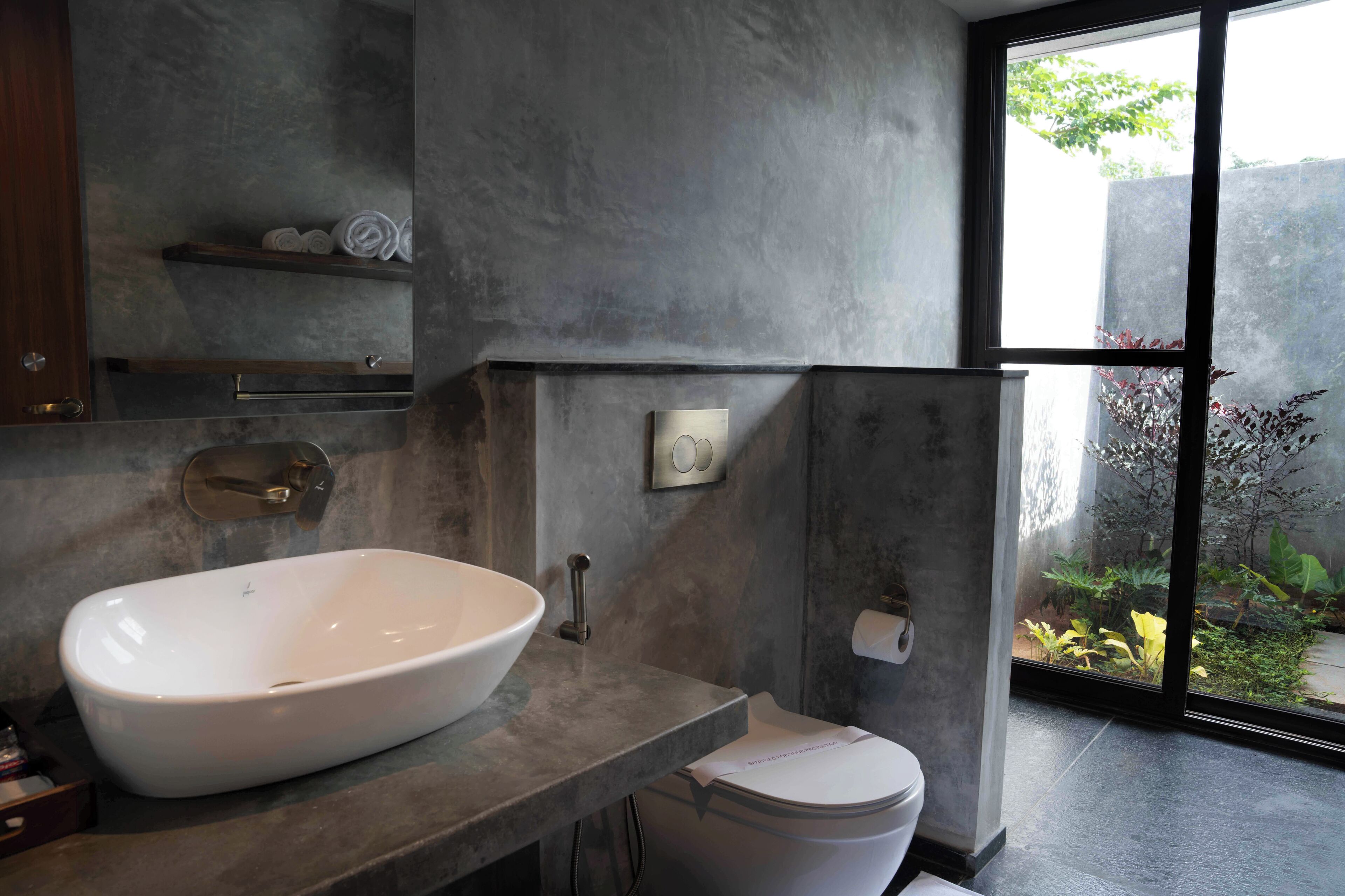 A modern bathroom with a large white sink, a toilet, and a shower area.