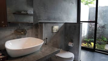 A modern bathroom with a large white sink, a toilet, and a shower area.