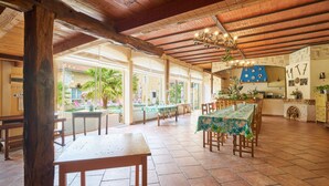 A spacious indoor area with wooden beams, a dining table with chairs, and a kitchen area. - Charming Gîte 'Le Pigeonnier' – Your Retreat in Périgord (Saint-Sulpice-de-Roumagnac)