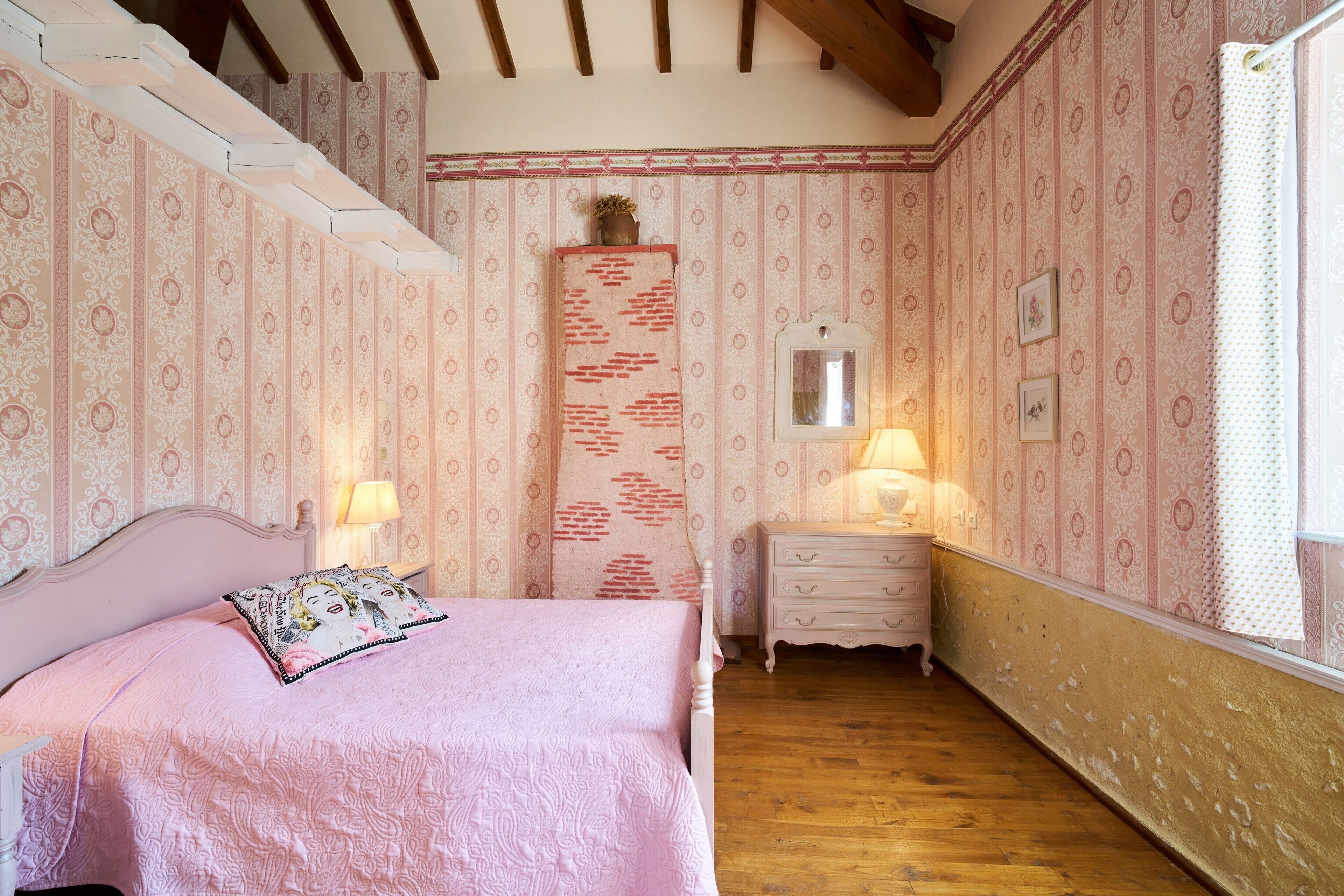 Een slaapkamer met een bed, een dressoir en een spiegel.