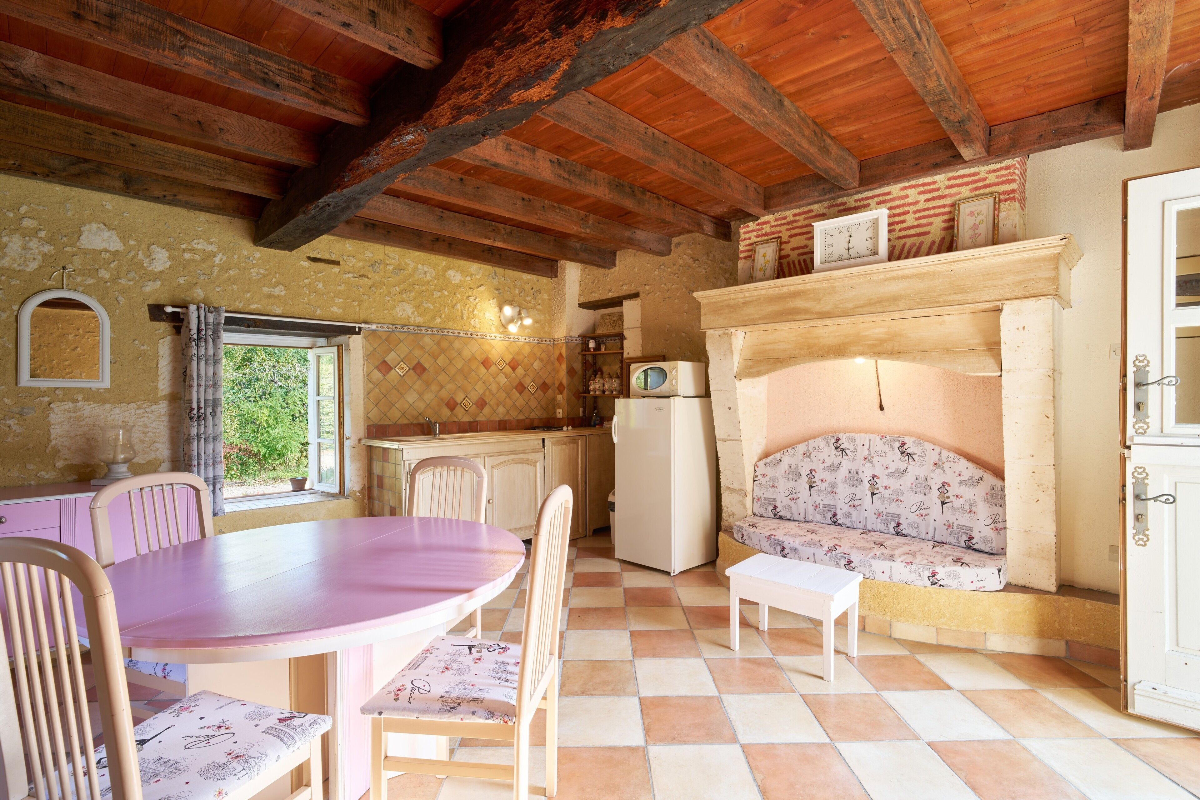 Een rustieke keuken met een houten plafond, een eettafel met stoelen, een bank en een open haard.