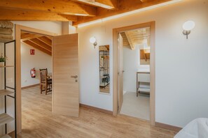 Ein Zimmer mit Holzboden, Holztür, Spiegel und einer Wandleuchte.