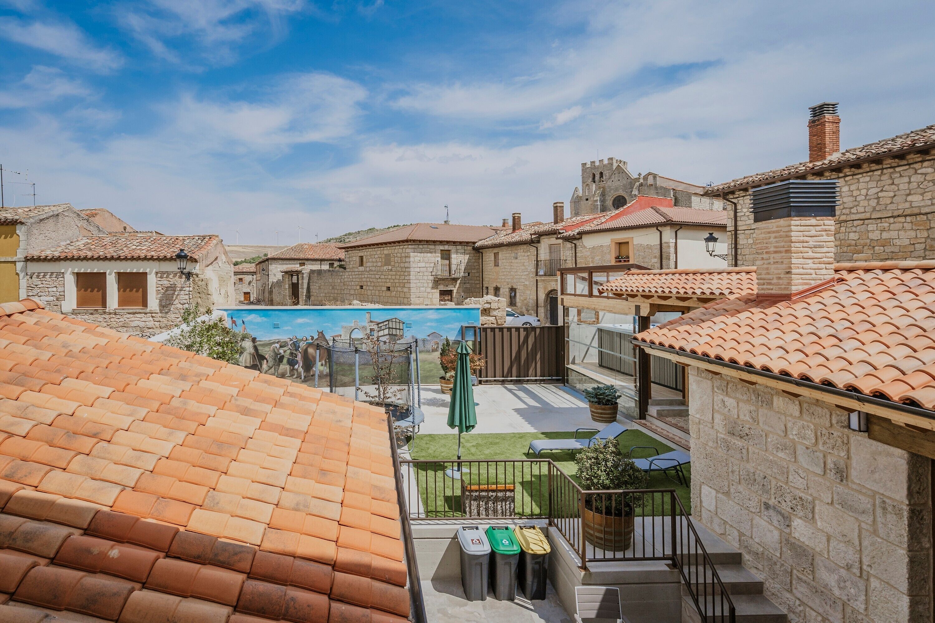 Un patio con piscina, edificios de piedra y un castillo al fondo.