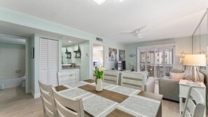A modern kitchen with a dining area, a ceiling fan, and a view of the city through large windows.