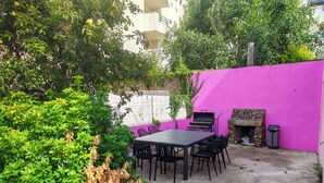A patio with a table and chairs, a barbecue grill, and a stone fireplace.