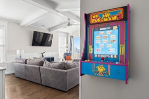 Een woonkamer met een grijze modulaire bank, een flatscreen televisie en een plafondventilator.