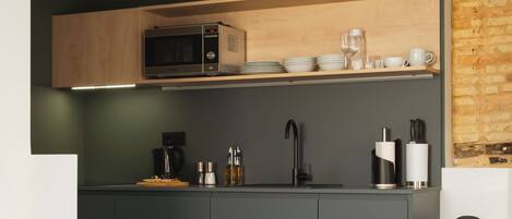Una cocina moderna con armarios oscuros, un microondas y una cafetera.