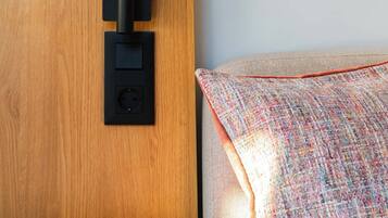 Eine Holzwand mit einer schwarzen Platte, einem kleinen Tisch und einem farbenfrohen Kissen auf einem Sofa.