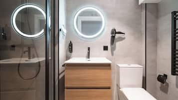 Un baño moderno con ducha de vidrio, tocador con espejo y retrete.