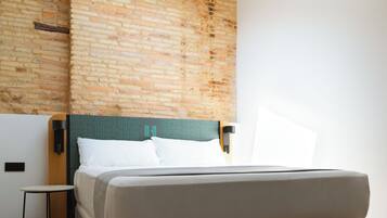 Un dormitorio moderno con una cama grande, una mesita de noche pequeña, cabecera con estampado geométrico y vigas de madera a la vista en el techo.