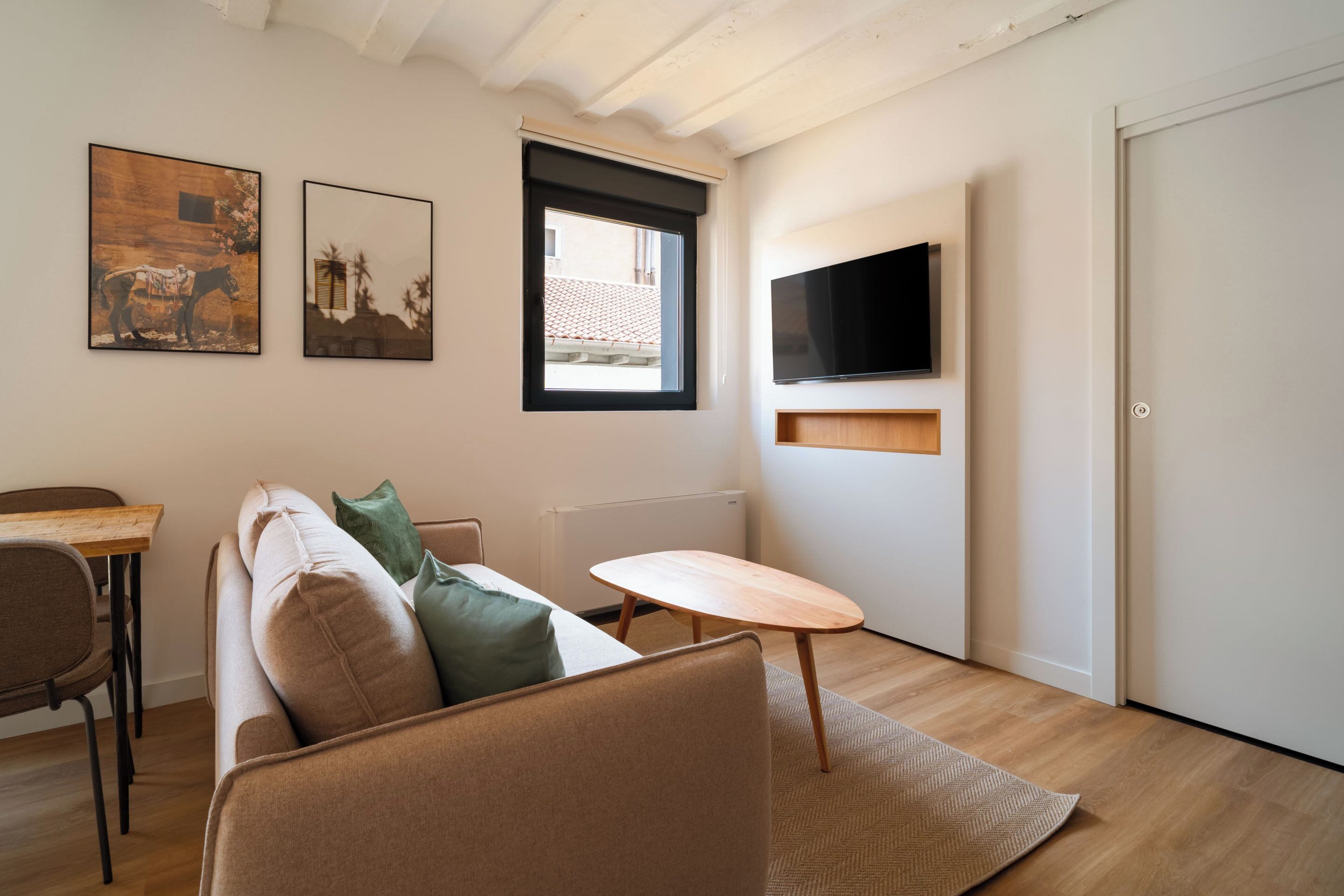 Een moderne woonkamer met een bank, een klein houten tafeltje en twee aan de muur bevestigde schilderijen.