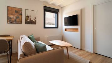 Een moderne woonkamer met een bank, een klein houten tafeltje en twee aan de muur bevestigde schilderijen.