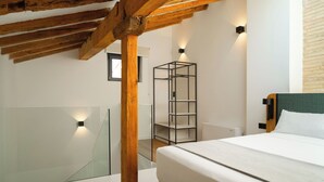 A bedroom with a bed, wooden beams, a glass wall, and a metal shelving unit. - Limehome Pamplona Hilarión Eslava (Pamplona)