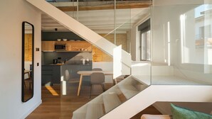 A modern interior with a staircase leading to a loft bedroom, a dining area, and a kitchen with wooden cabinets and a microwave. - Limehome Pamplona Hilarión Eslava (Pamplona)