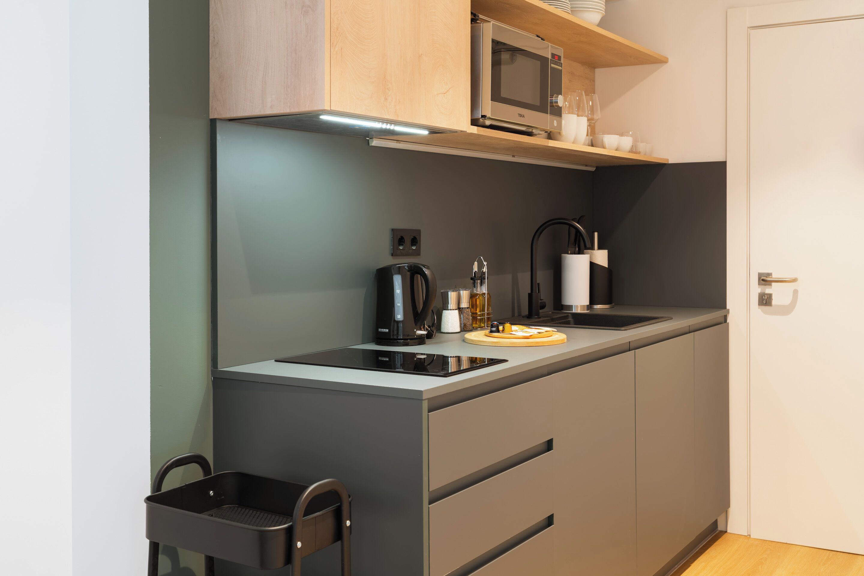 Una cocina compacta con microondas, cafetera y una pequeña encimera.