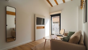 A modern living room with a wooden floor, a sofa, a coffee table, and a TV mounted on the wall. - Limehome Pamplona Hilarión Eslava (Pamplona)
