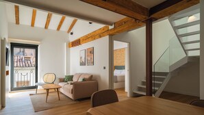 A spacious living room with a wooden dining table, a sofa, and a staircase. - Limehome Pamplona Hilarión Eslava (Pamplona)