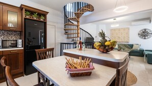 Una cocina moderna con una escalera en espiral, un comedor con una cesta de pan y un frutero en la isla.
