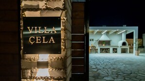 Señal de 'Villa Cela' con fachada de piedra y una moderna zona de cocina al aire libre.