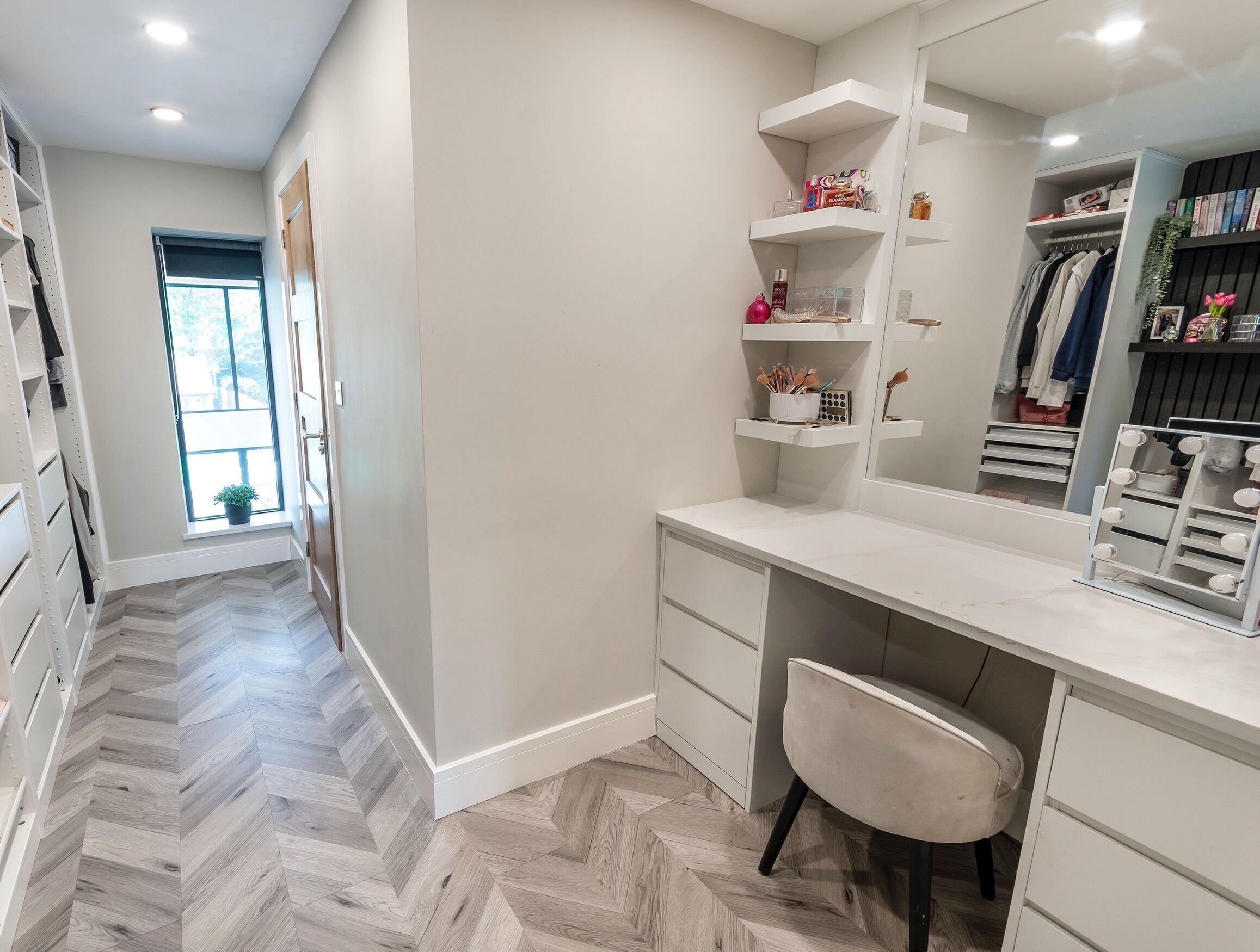 A modern, well-lit walk-in closet with organized shelves and a large mirror.
