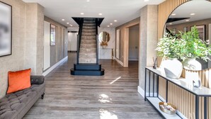 A modern interior with a central staircase, a sofa with cushions, a console table with decorative items, and a large mirror. - 5 Bed Villa-sleeps 10-hot Tub-bar & Pool Table (Doncaster)