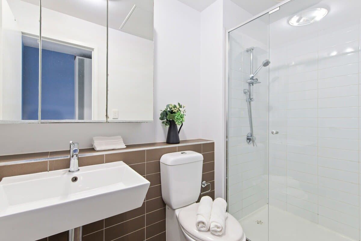 Ein modernes Badezimmer mit Waschbecken, Toilette und Duschkabine aus Glas.