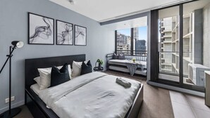 A modern bedroom with a large bed, a desk, and a balcony with a city view. - City-view Studio Near Southern Cross (Melbourne)