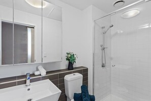 A modern bathroom with a white sink, a glass shower enclosure, and a mirror above the sink.