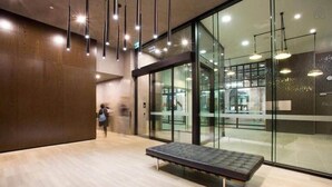 A modern interior with a bench, glass walls, and hanging lights. - City-view Studio Near Southern Cross (Melbourne)