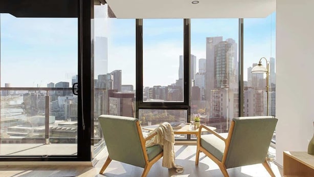 A modern living room with large windows, two chairs, a small table, and a lamp.