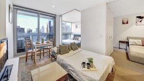 Une chambre d’hôtel moderne dotée d’un grand lit, d’un coin repas et offrant une vue sur la ville.