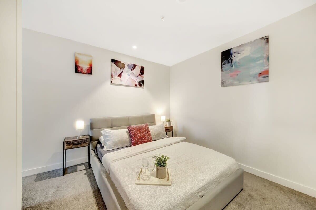 Une chambre à coucher moderne, avec un lit, des tables de chevet et des œuvres d’art accrochées aux murs.