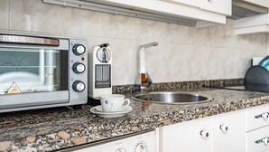 Una cocina con microondas, cafetera y pileta.