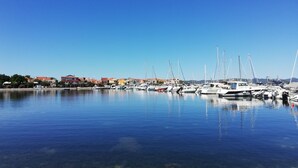 A marina with boats docked, clear blue water, and buildings in the background.