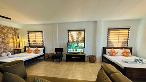 Une chambre d’hôtel avec deux lits simples, un canapé, une télévision et une petite table.