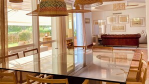 A dining area with a glass-top table, wicker chairs, and hanging wicker lamps. - Unique front line golf villa in Marbella (Marbella)