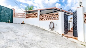 A gated residential area with a paved driveway, a small potted plant, and a hose coiled against the wall. - Villa 'Jema' with Sea Views, Private Pool and Air Conditioning (torrox)