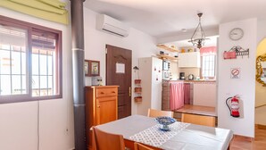 A dining area with a table, chairs, and a kitchen in the background. - Villa 'Jema' with Sea Views, Private Pool and Air Conditioning (torrox)