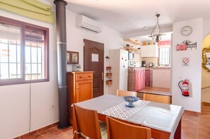 A dining area with a table, chairs, and a kitchen in the background.