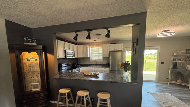 A modern kitchen with a central island, bar stools, and a decorative cabinet. - Hey friends, welcome to Maggie’s Place to relax and enjoy some peace and quiet  (Rogersville)