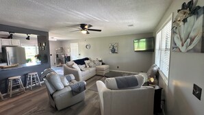 A modern living room with a sofa, a coffee table, and a dining area with stools. - Hey friends, welcome to Maggie’s Place to relax and enjoy some peace and quiet  (Rogersville)