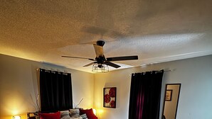 A bedroom with a bed, a ceiling fan, a nightstand, a bedside table, a rug, and a mirror. - Hey friends, welcome to Maggie’s Place to relax and enjoy some peace and quiet  (Rogersville)