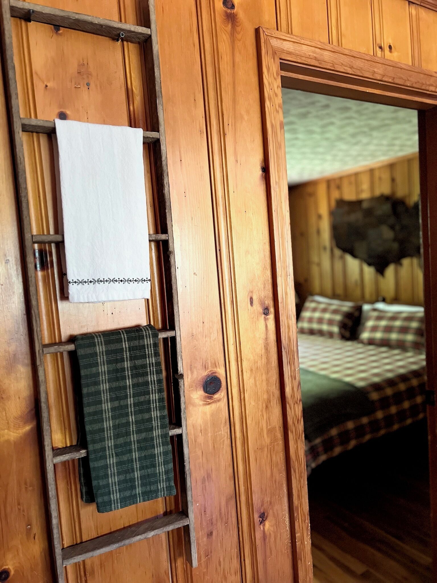 Un intérieur en bois comprenant un lit, une échelle et une étagère avec une serviette et un objet décoratif.